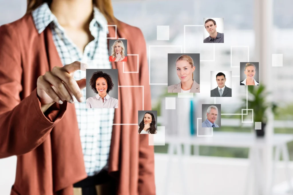 A person gestures at a digital display of interconnected profiles in an office environment.