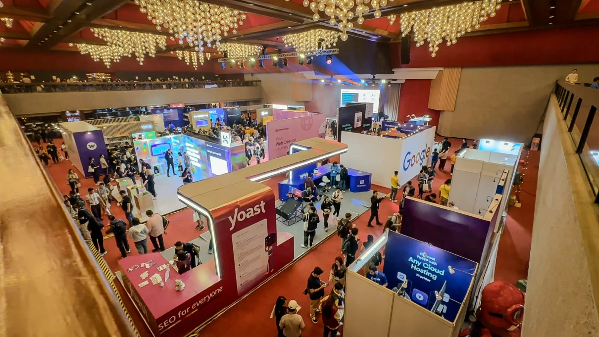 An aerial view of various sponsor booths at WordCamp Asia 2025, showcasing colorful displays and attendees interacting in a lively exhibition area