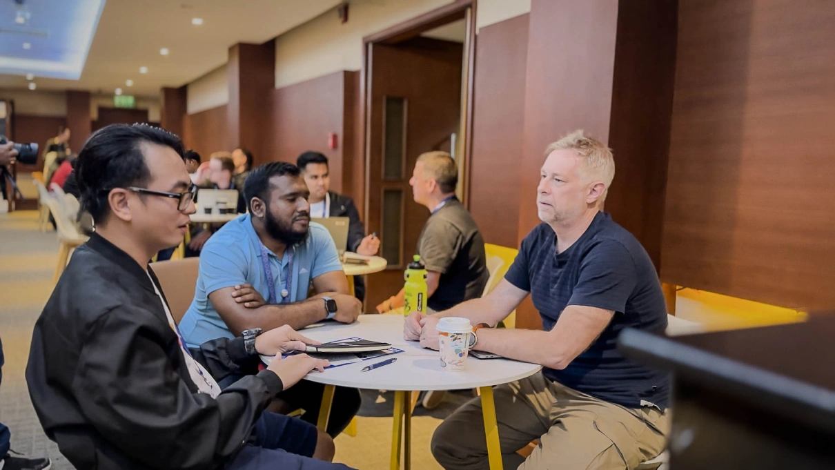 Several individuals and developers engaged in discussion around tables in a conference room during the Human Library Session at WordCamp Asia 2025