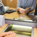 Clerk counting cash money at bank office.