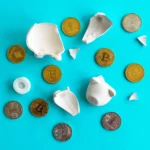 Broken white piggy bank with scattered Bitcoin and Ethereum coins on a blue background, symbolizing financial loss and tech’s playbook in stablecoins
