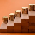 Coins stacked on wooden blocks, representing the intersection of traditional banking and emerging stablecoin technology.